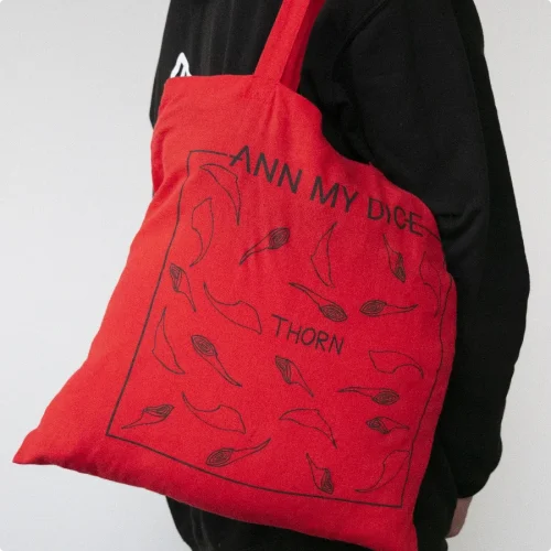 Ann My Dice red tote bag with Thorn album art, worn on shoulder